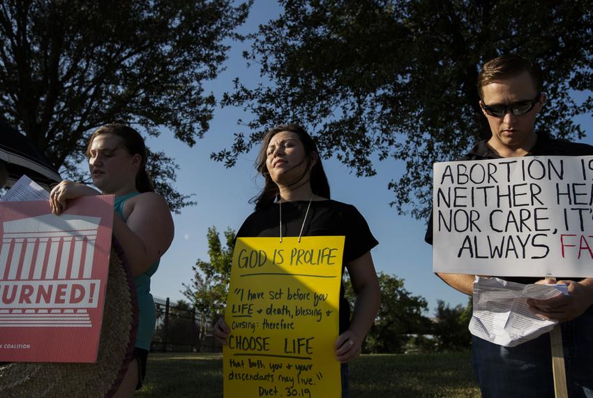 From left: Vienne Crook, Tara Beulah and Xavier Heim listen as Pastor Laurence White reads a prayer at a rally in support of the Supreme Court’s decision to overturn Roe v. Wade in front of Planned Parenthood’s offices in Houston on June 24, 2022.